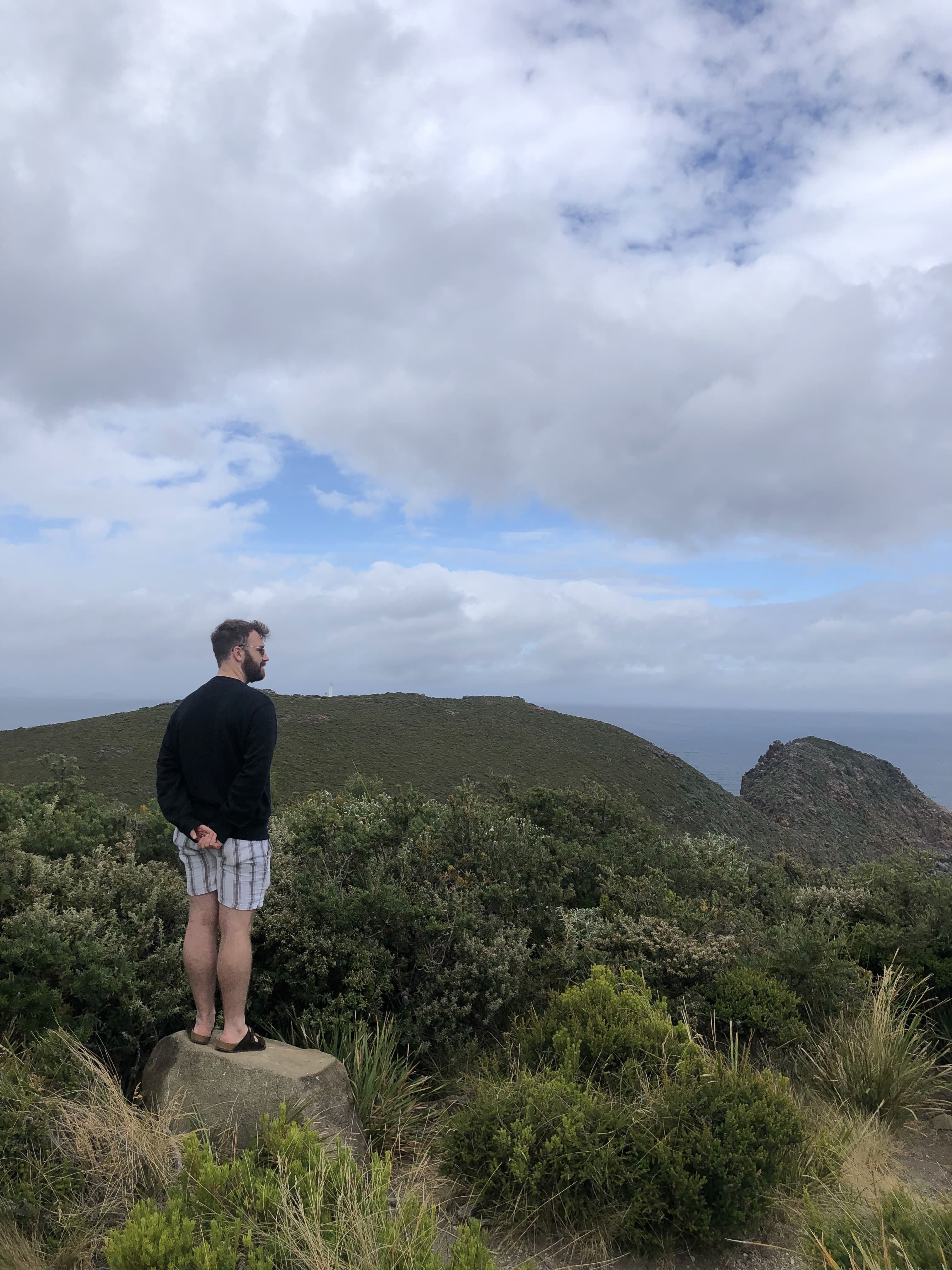 Greg standing on a clifftop in Tasmania looking off into the distance